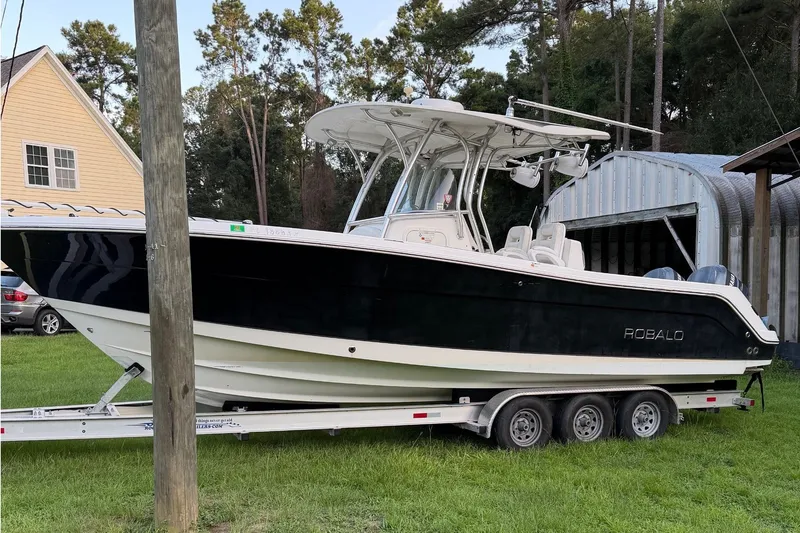 Slide: The Image of A 2007 Robalo R300 Center Console boat on a trailer in a yard. - 1