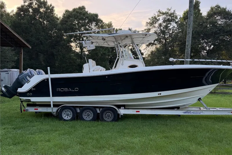 The Image of A 2007 Robalo R300 Center Console boat on a trailer, surrounded by trees. - 0