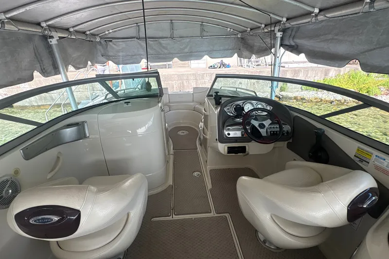 Slide: The Image of Interior of a 2005 Azure AZ240 boat with steering wheel and seating under canopy. - 9