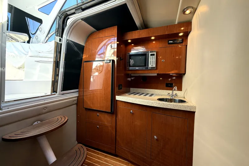Slide: The Image of 2006 Regal Commodore 3760 IO yacht interior with kitchenette, featuring wood cabinetry and modern appliances. - 17