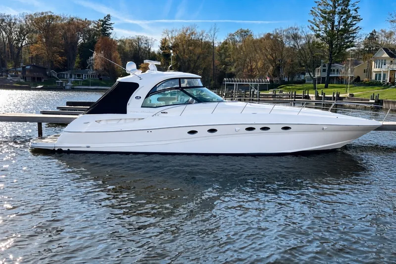 Slide: The Image of 2003 Sea Ray 500 Sundancer yacht docked on a serene lake with autumn trees. - 1