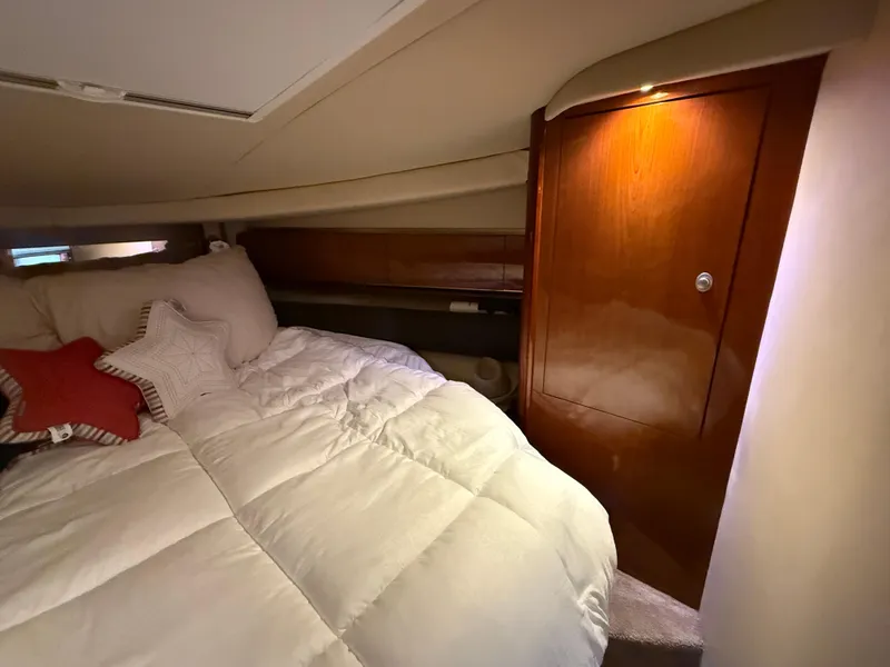 Slide: The Image of 2003 Sea Ray 500 Sundancer cabin interior with cozy bed and wooden cabinetry. - 22