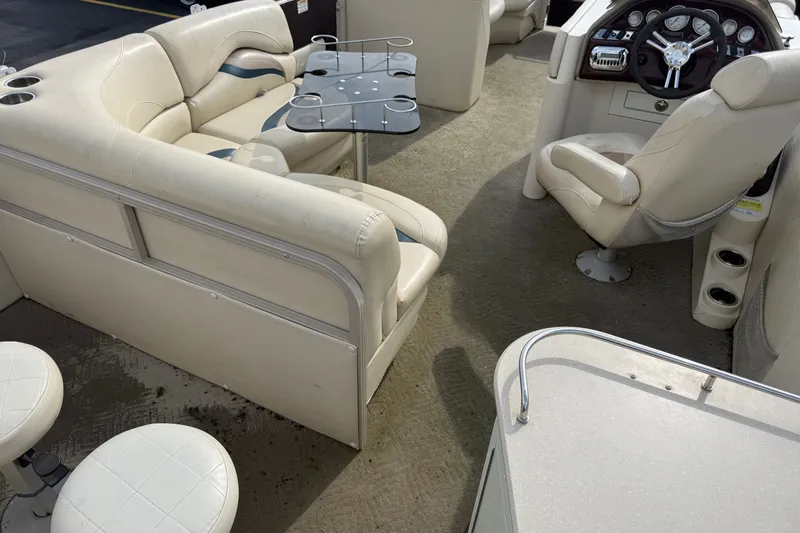 Slide: The Image of Interior of a 2010 Sylvan 8525 Mandalay pontoon boat with beige seating and helm. - 16