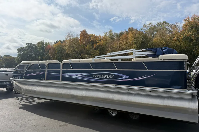 The Image of 2010 Sylvan 8525 Mandalay pontoon boat parked outdoors with autumn trees in background. - 0