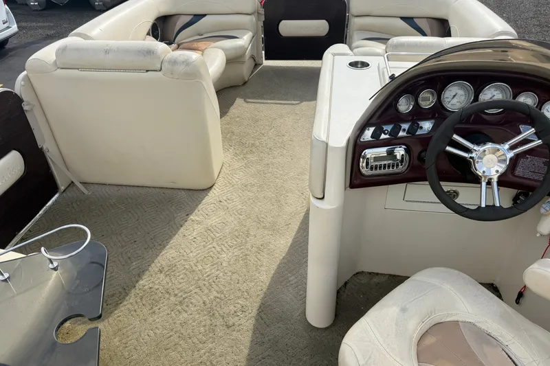 Slide: The Image of Interior of a 2010 Sylvan 8525 Mandalay pontoon boat with beige seating and steering console. - 17