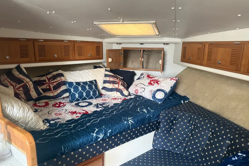 Slide: The Image of Cozy cabin interior of 1995 Cabo 35 Express with nautical-themed bedding and wooden storage cabinets. - 8