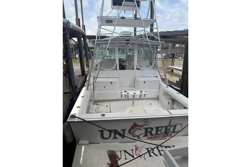 Slide: The Image of 1995 Cabo 35 Express boat docked, featuring fishing equipment and "Unreel" branding. - 2