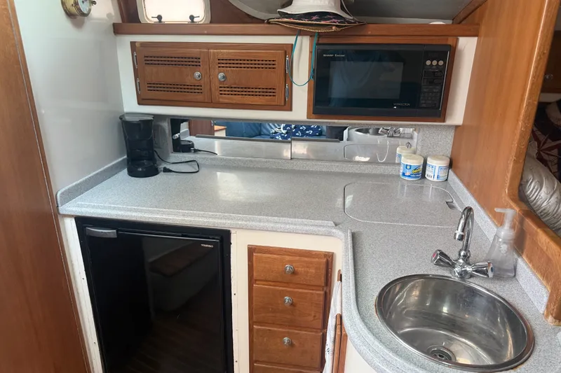 Slide: The Image of 1995 Cabo 35 Express boat kitchen with sink, microwave, and compact fridge. - 9