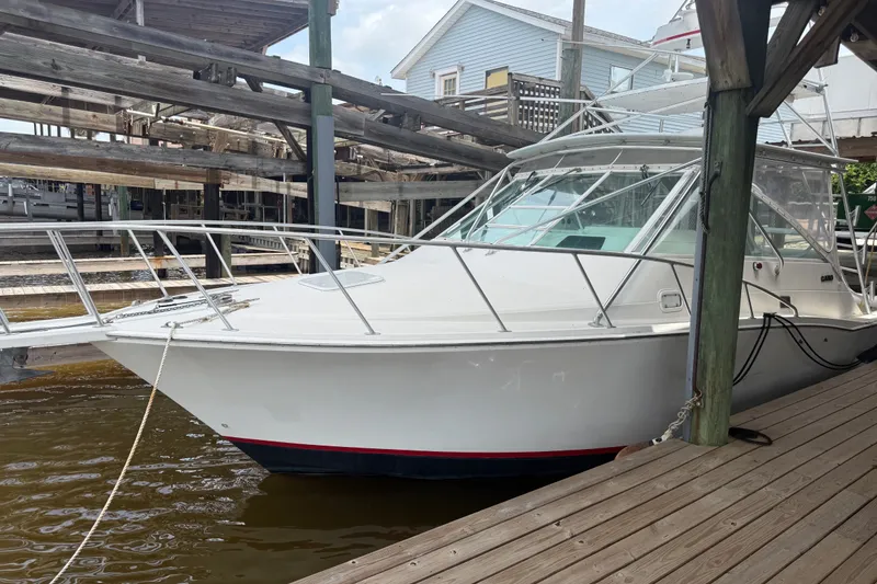 The Image of 1995 Cabo 35 Express boat docked at a marina, featuring a sleek white exterior. - 4