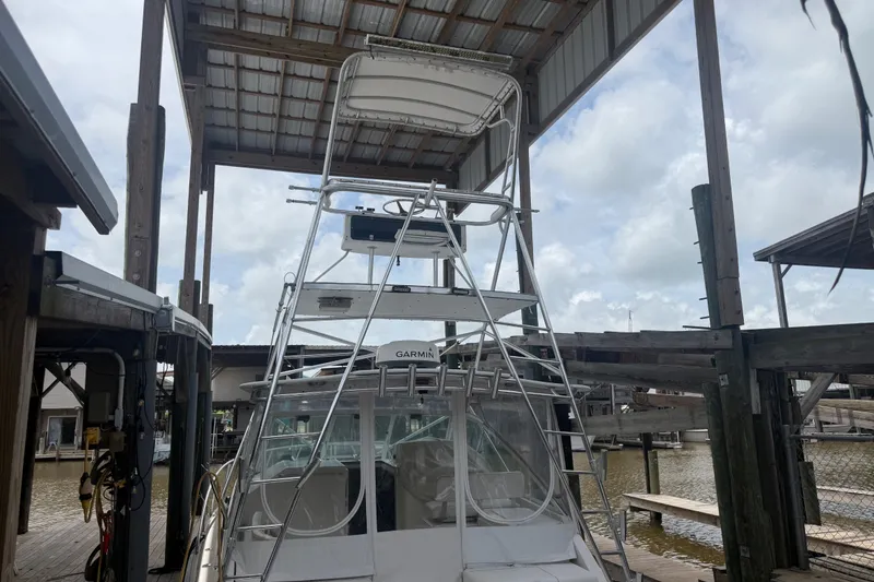 Slide: The Image of 1995 Cabo 35 Express boat docked under a covered structure, featuring a tall tower. - 21