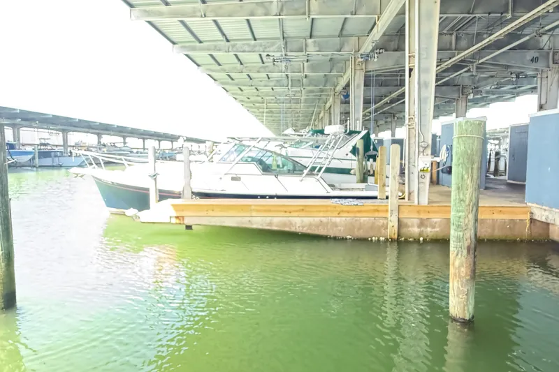 Slide: The Image of 2002 Mainship Pilot 34 docked in a covered marina with green water. - 3