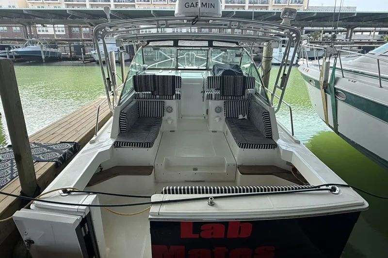 Slide: The Image of 2002 Mainship Pilot 34 boat docked, featuring striped seating and spacious deck area. - 5