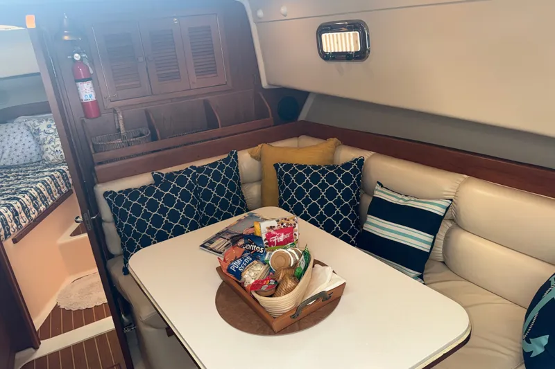 Slide: The Image of Cozy interior of 2002 Mainship Pilot 34 with cushions and snacks on the table. - 15