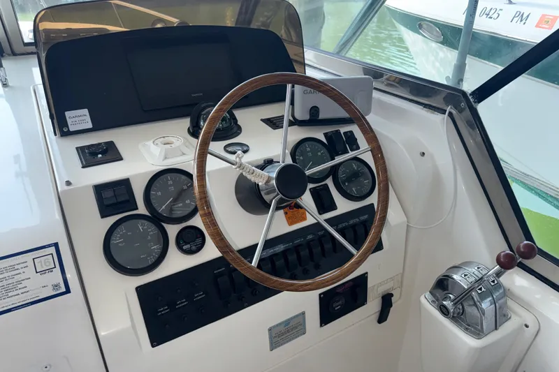 Slide: The Image of 2002 Mainship Pilot 34 helm with gauges, wooden steering wheel, and control panel. - 20
