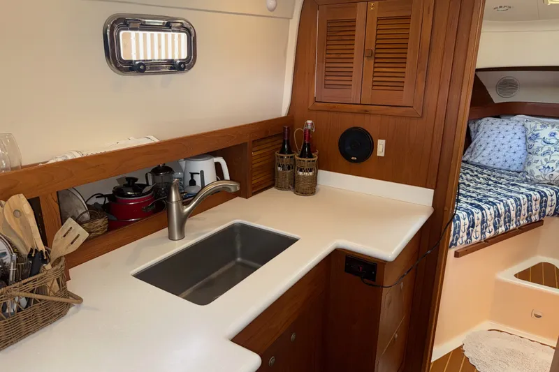 Slide: The Image of 2002 Mainship Pilot 34 interior with kitchenette, sink, and cozy sleeping area. - 11