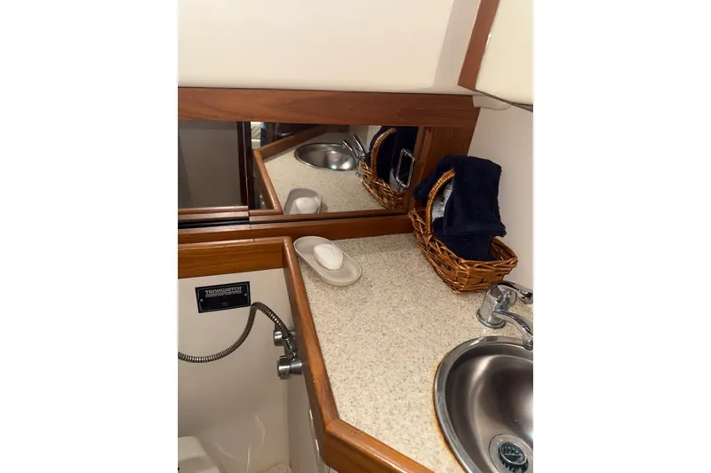 Slide: The Image of 2002 Mainship Pilot 34 bathroom with sink, mirror, and wicker baskets. - 14