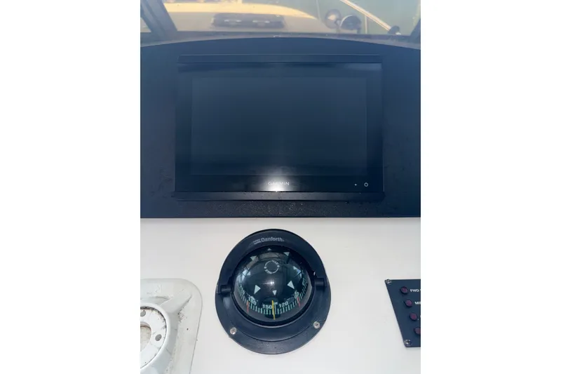 Slide: The Image of Control panel of a 2002 Mainship Pilot 34 boat with compass and screen. - 21