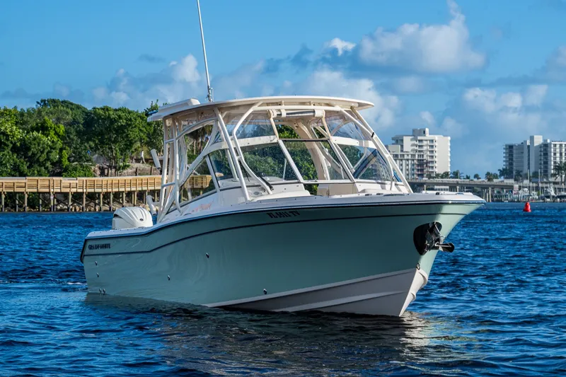 Slide: The Image of 2024 Grady-White Freedom 275 boat cruising on a sunny day near a city waterfront. - 4