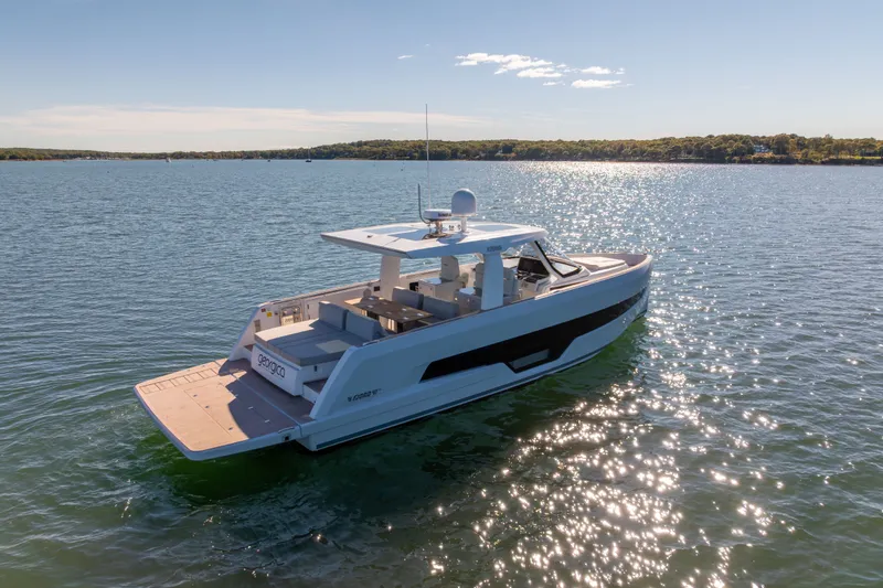Slide: The Image of 2023 Fjord 41 XL yacht cruising on a sunny lake with scenic shoreline. - 4