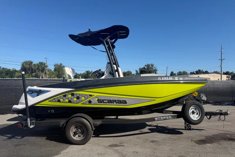 The Image of 2017 Scarab 195 ID boat in vibrant green on a trailer, parked outdoors. - 0