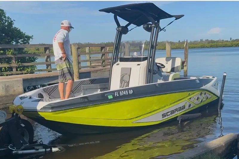 The Image of 2017 Scarab 195 ID boat docked with a person standing on it. - 2