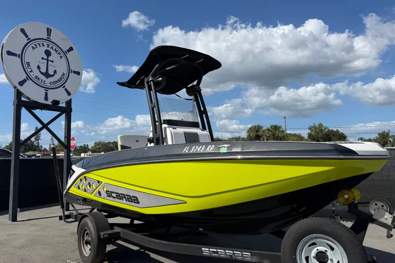 The Image of 2017 Scarab 195 ID boat in bright yellow on a trailer, under a clear blue sky. - 0