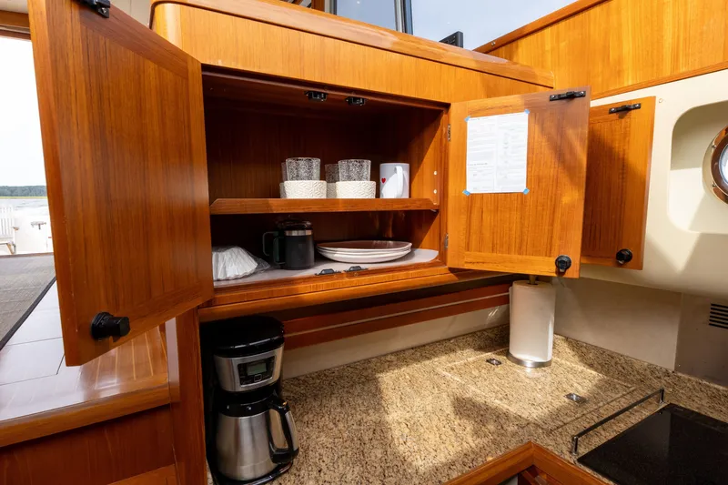 Slide: The Image of Wooden kitchen cabinet with open doors, revealing dishes and glasses, on a 2009 Grand Banks 45 Eastbay SX yacht. - 53