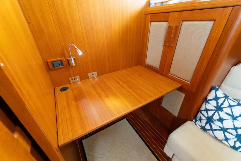 Slide: The Image of 2009 Grand Banks 45 Eastbay SX interior with wooden desk, lamp, and storage cabinets. - 60