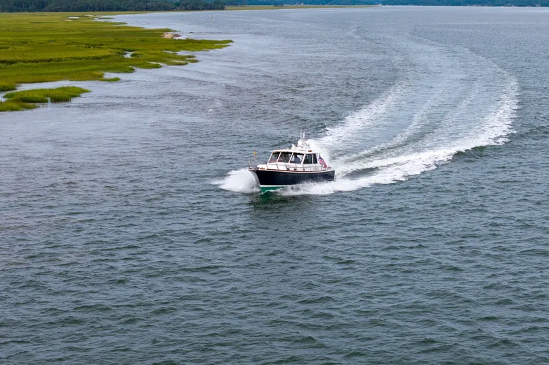 Slide: The Image of 2009 Grand Banks 45 Eastbay SX cruising on open water near a grassy shoreline. - 93
