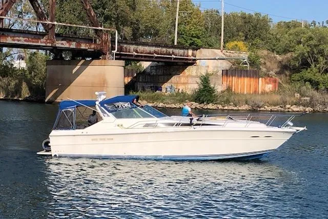Slide: The Image of 1988 Sea Ray 390 Express Cruiser on a river near a rusty bridge. - 1