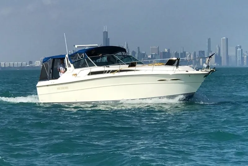 The Image of 1988 Sea Ray 390 Express Cruiser on water with city skyline in background. - 0