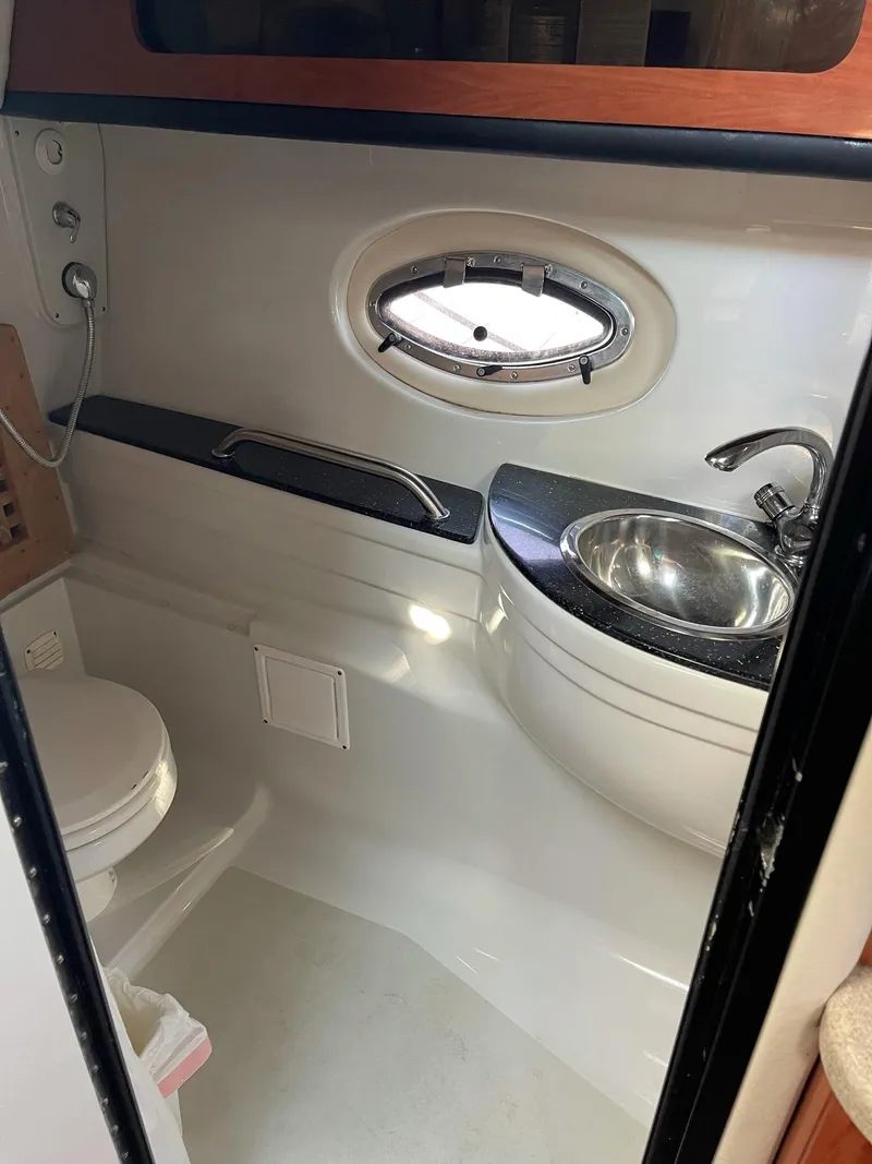 Slide: The Image of 2008 Crownline 340 CR boat bathroom with sink, toilet, and porthole window. - 42