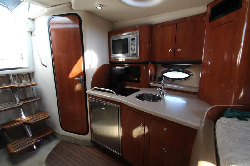 Slide: The Image of 2008 Crownline 340 CR yacht interior with kitchenette, featuring wood cabinets, sink, and microwave. - 33