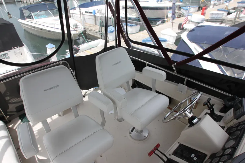 Slide: The Image of 1990 Silverton 34 Convertible boat cockpit with white seats and steering wheel. - 44