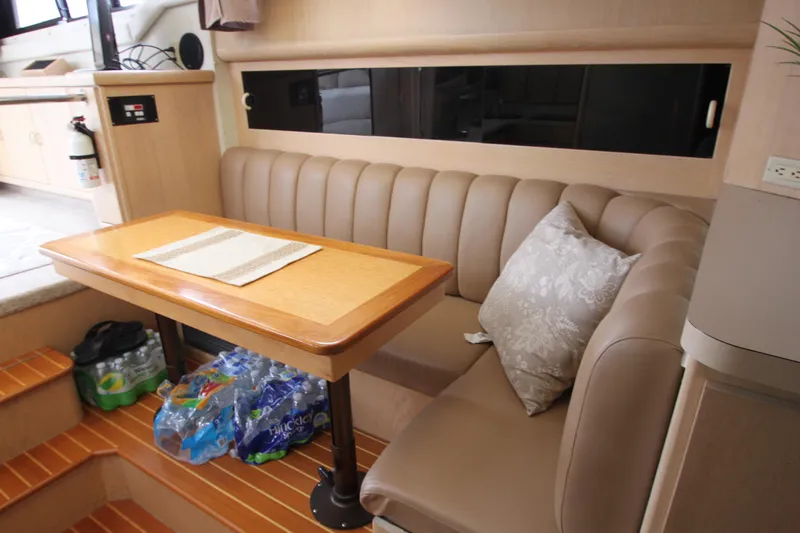 Slide: The Image of 1990 Silverton 34 Convertible interior with dining area, cushioned seating, and wooden table. - 30