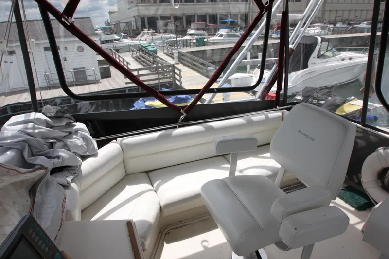 Slide: The Image of 1990 Silverton 34 Convertible boat interior with white seating and marina view. - 45