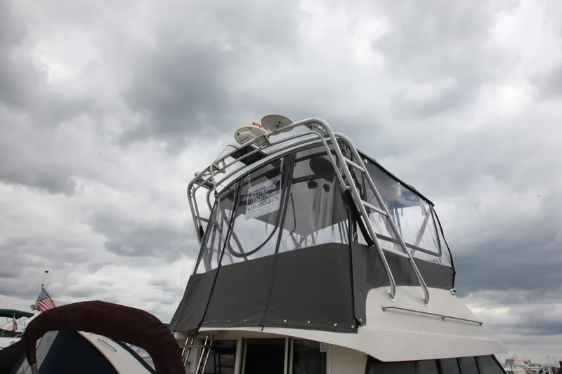 Slide: The Image of 1990 Silverton 34 Convertible boat with enclosed flybridge under cloudy sky. - 47