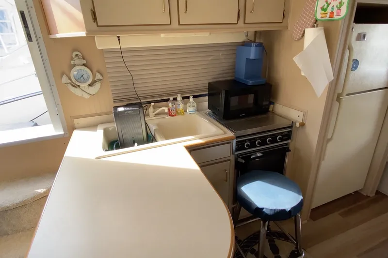 Slide: The Image of Compact kitchen area in a 2000 Gibson 37 Sport Series boat, featuring a stove, sink, and microwave. - 16