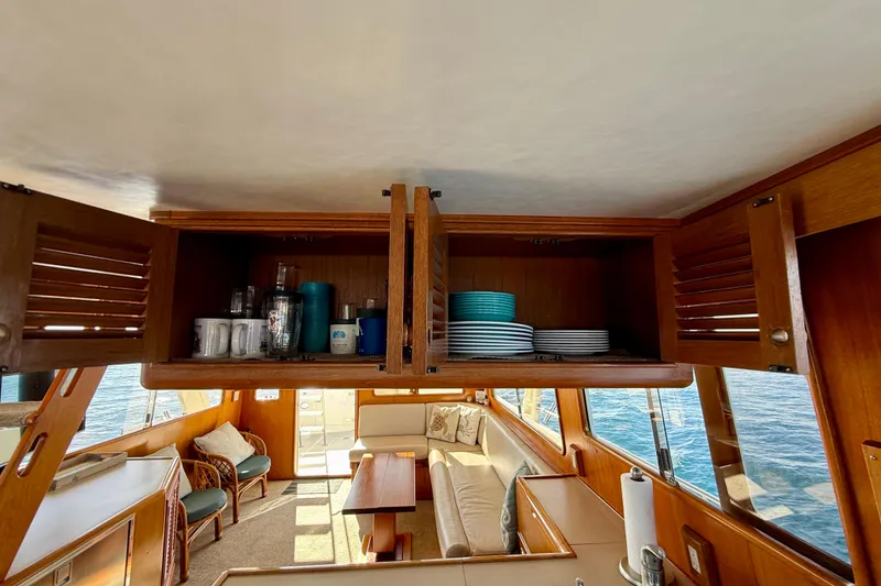 Slide: The Image of Interior of 1997 Offshore Yachts 48 Sedan with open wooden cabinets and ocean view. - 52