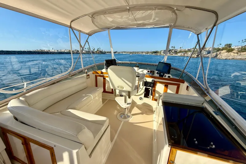 Slide: The Image of 1997 Offshore Yachts 48 Sedan helm with ocean view, featuring comfortable seating and navigation equipment. - 75