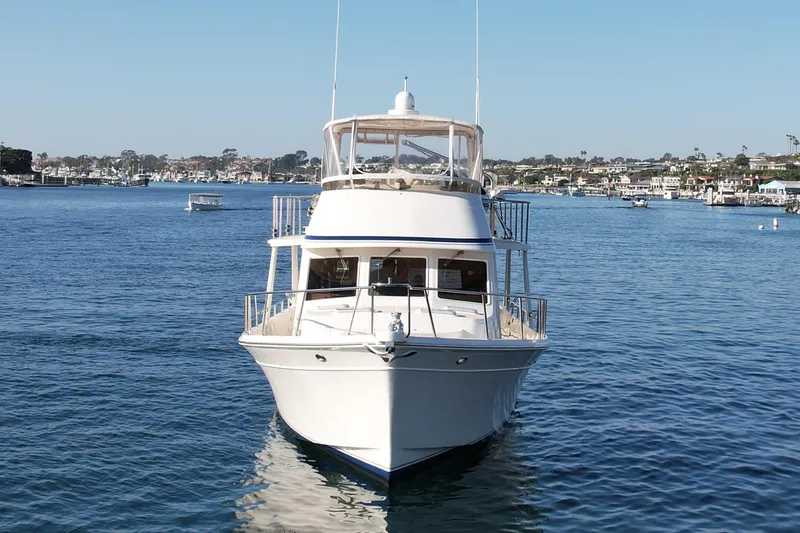 Slide: The Image of 1997 Offshore Yachts 48 Sedan on calm water, clear sky, coastal background. - 1
