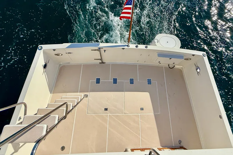 Slide: The Image of 1997 Offshore Yachts 48 Sedan deck with American flag, cruising on water. - 71
