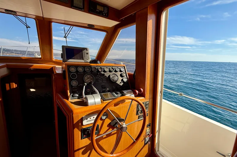 Slide: The Image of 1997 Offshore Yachts 48 Sedan helm with ocean view, featuring classic wooden steering wheel. - 31