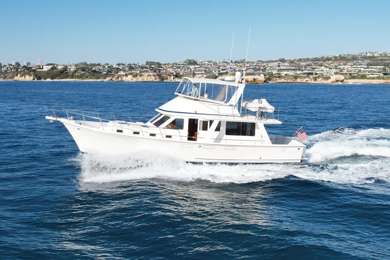 Slide: The Image of 1997 Offshore Yachts 48 Sedan cruising on blue ocean near coastal cityscape. - 3