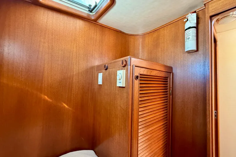 Slide: The Image of Wood-paneled interior of 1997 Offshore Yachts 48 Sedan with fire extinguisher and vented cabinet. - 24