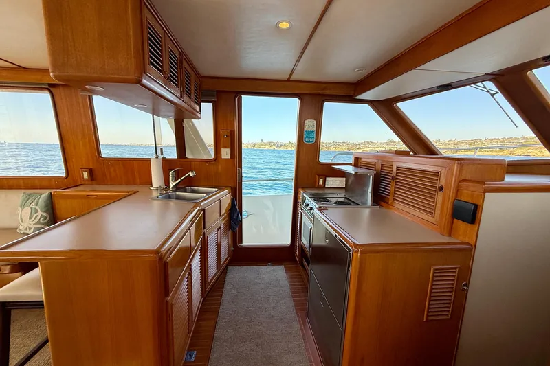 Slide: The Image of Interior of 1997 Offshore Yachts 48 Sedan, featuring a wooden kitchen with ocean view. - 50