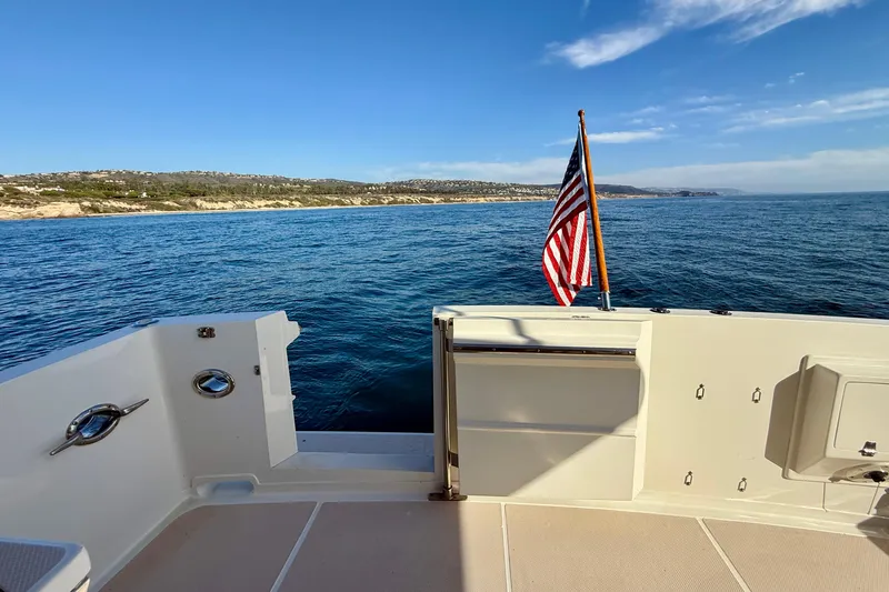Slide: The Image of 1997 Offshore Yachts 48 Sedan, ocean view with American flag, clear sky. - 63