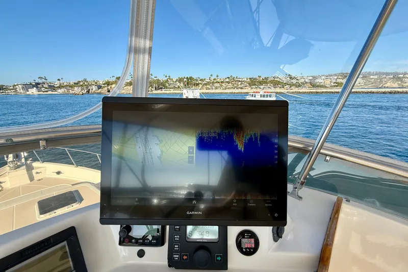 Slide: The Image of Cockpit view of 1997 Offshore Yachts 48 Sedan with navigation display, coastal background. - 72