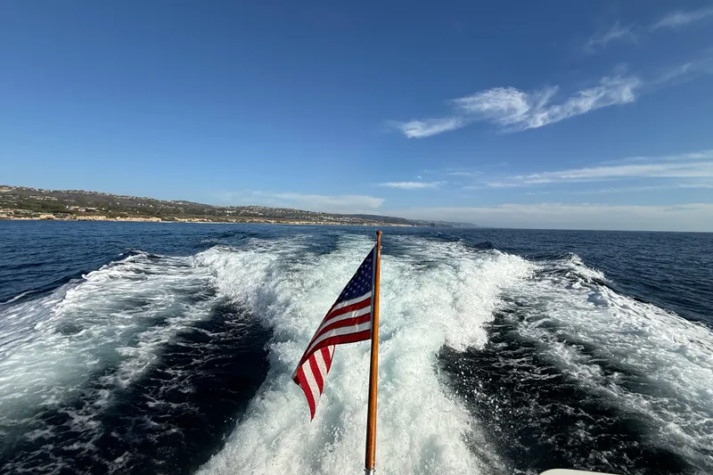Slide: The Image of Wake of 1997 Offshore Yachts 48 Sedan with American flag, ocean view. - 92