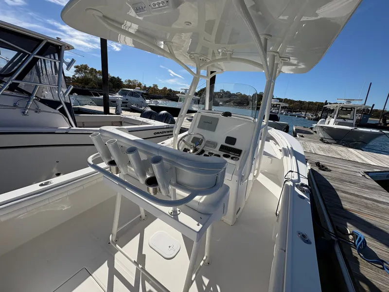 Slide: The Image of A 2017 Regulator 23 boat with T-top, helm console, and rod holders, docked at a marina. - 11
